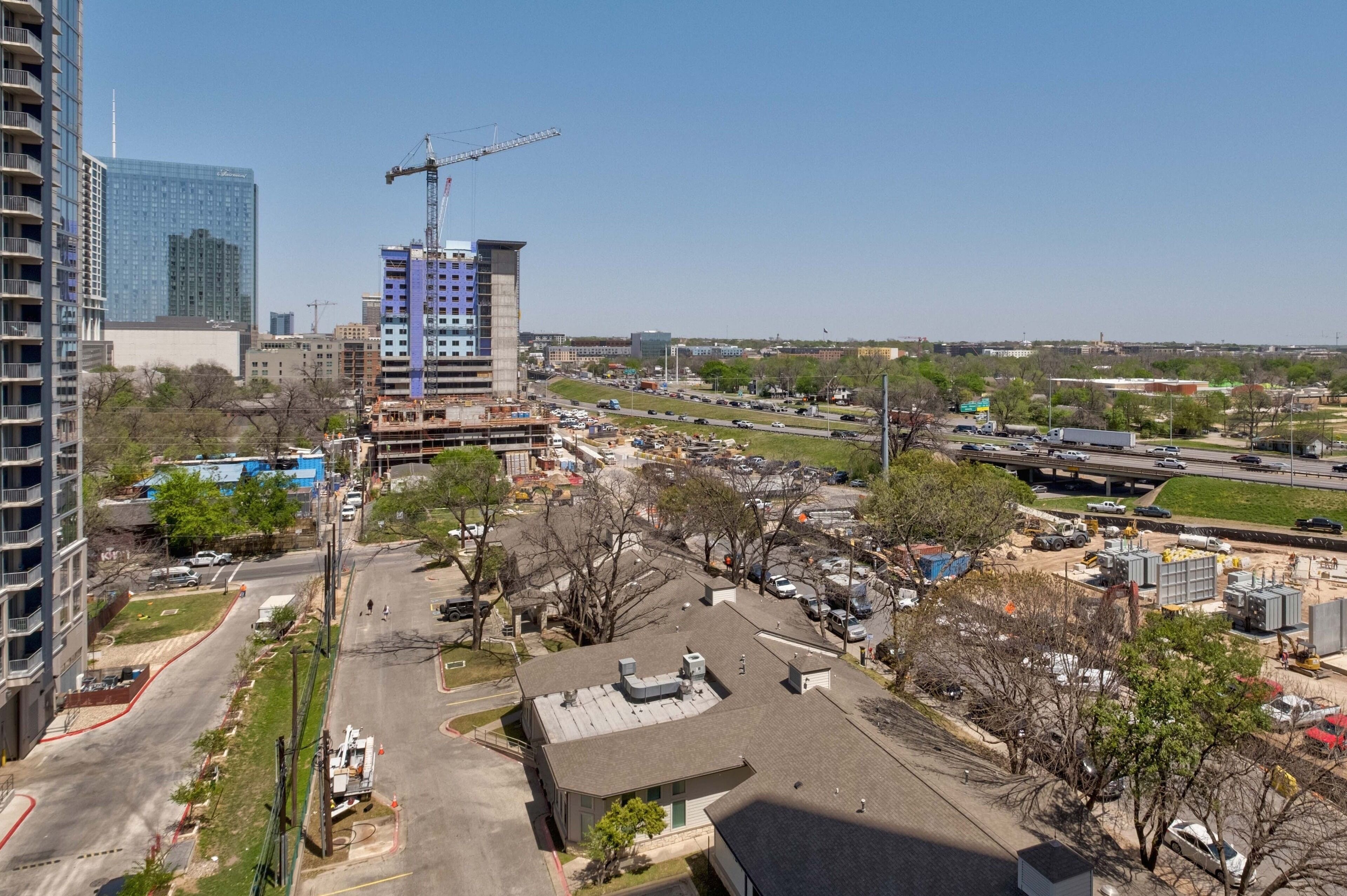 A construction site with a crane, a parking lot, and a highway in the background.
