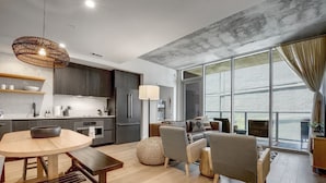 A modern kitchen with dark cabinets, a round wooden table, and a hanging light fixture.
