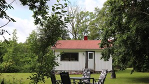 A small white building with a red roof, surrounded by lush greenery. - 4 Person Holiday Home in Karl Gustav (Karl Gustav)