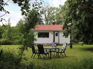 A small white building with a red roof, surrounded by lush greenery. - 4 Person Holiday Home in Karl Gustav (Karl Gustav)