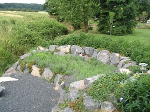 A garden with a stone border, various plants, and a tree in the background. - Aan de Frankenbeek (Sinzig)