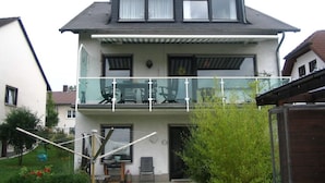 A two-story house with a balcony, a garage, and a garden area.