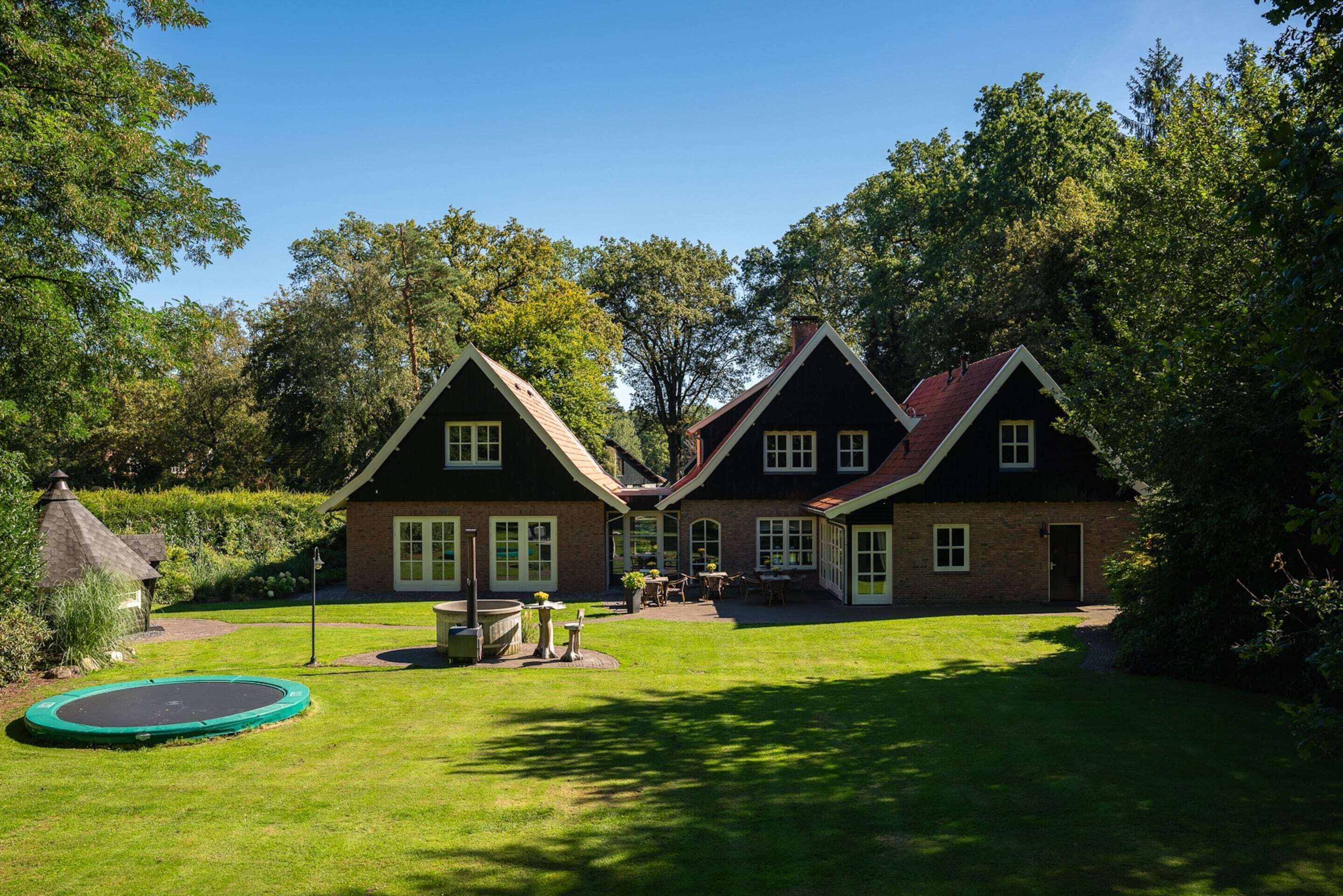 A two-story house with a brick exterior, a well-maintained lawn, and a trampoline in the yard.