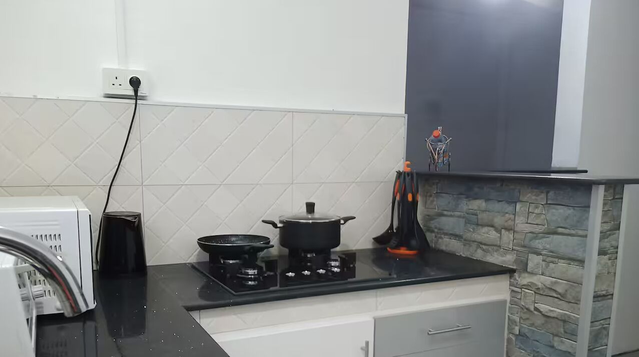 A kitchen with a gas stove, a pot, a kettle, and a toaster.