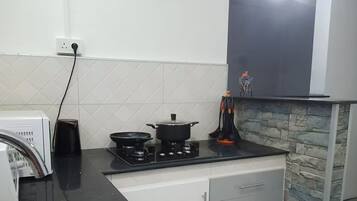 A kitchen with a gas stove, a pot, a kettle, and a toaster.