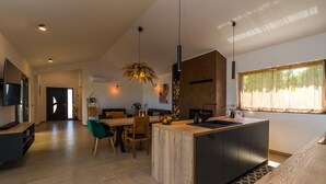 Une cuisine moderne dotée d’un îlot central, d’un coin repas et d’un téléviseur fixé au mur.