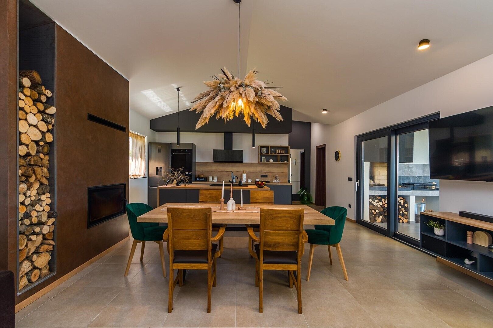 A modern kitchen with a central island, a dining area with a wooden table and chairs, and a large window overlooking the city.