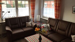 A cozy living room with two brown sofas, a checkered table, and a vase of flowers. - Holiday Home Seehase (Norden)