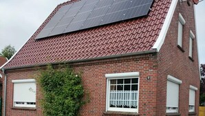 A house with a sloped red-tiled roof, solar panels, and a brick exterior. - Holiday Home Seehase (Norden)