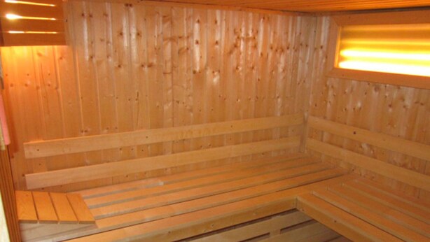 A wooden sauna with benches and a sloped ceiling. - Holiday Home Seehase (Norden)