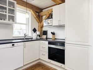 A modern kitchen with white cabinetry, a Bosch dishwasher, a coffee maker, and a microwave.