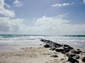 A beach with a rocky shoreline and waves crashing onto the sand.