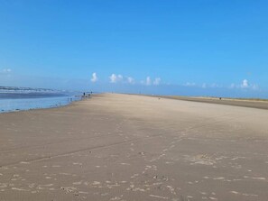 Ein weiter, leerer Strand mit blauem Himmel und ruhiger See.