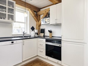 A modern kitchen with white cabinetry, a Bosch dishwasher, a microwave, and a coffee maker.