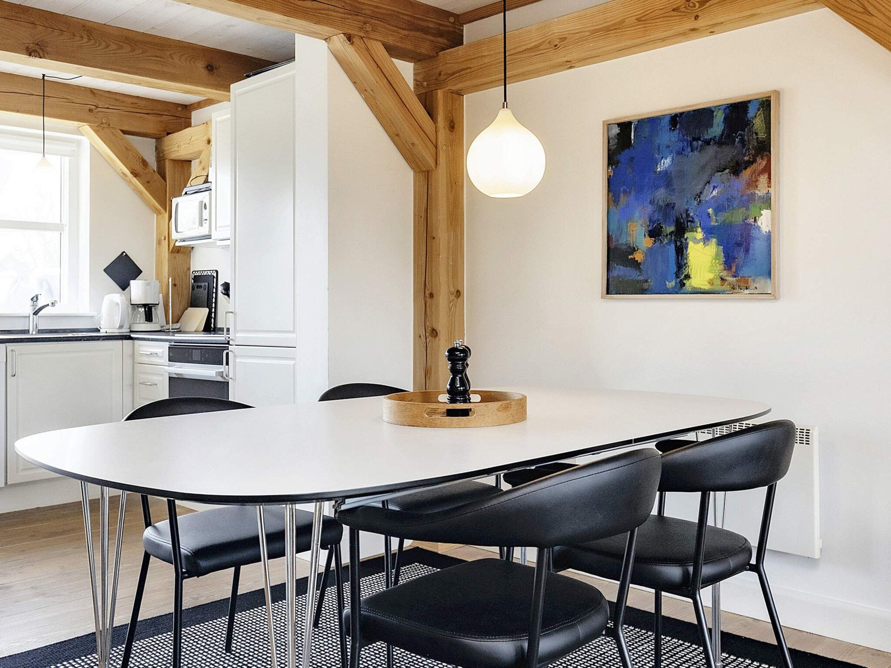 A modern kitchen with white cabinets, a black countertop, and a dining table with four chairs.