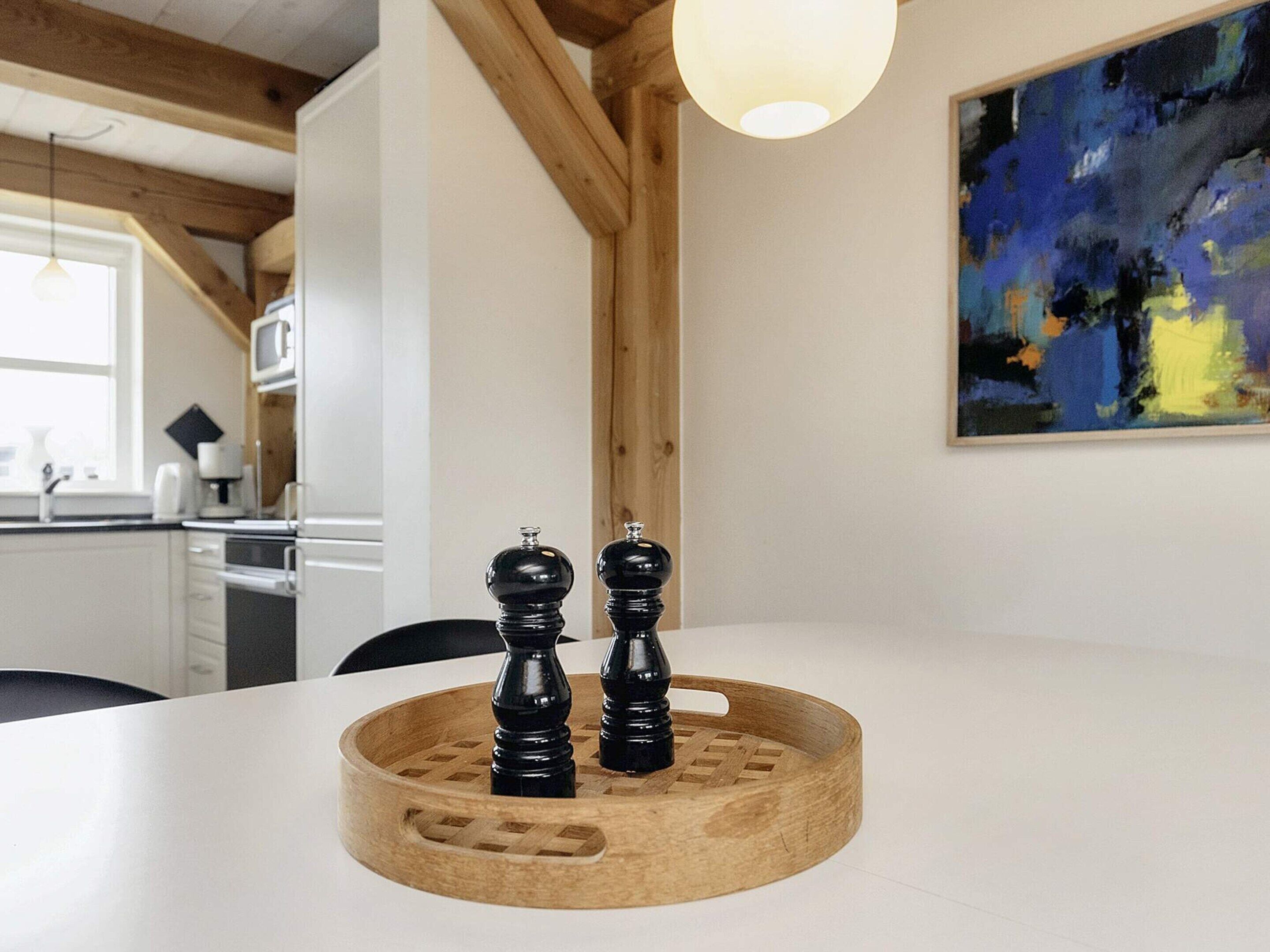 A modern kitchen with wooden beams, a white countertop, and a painting on the wall.