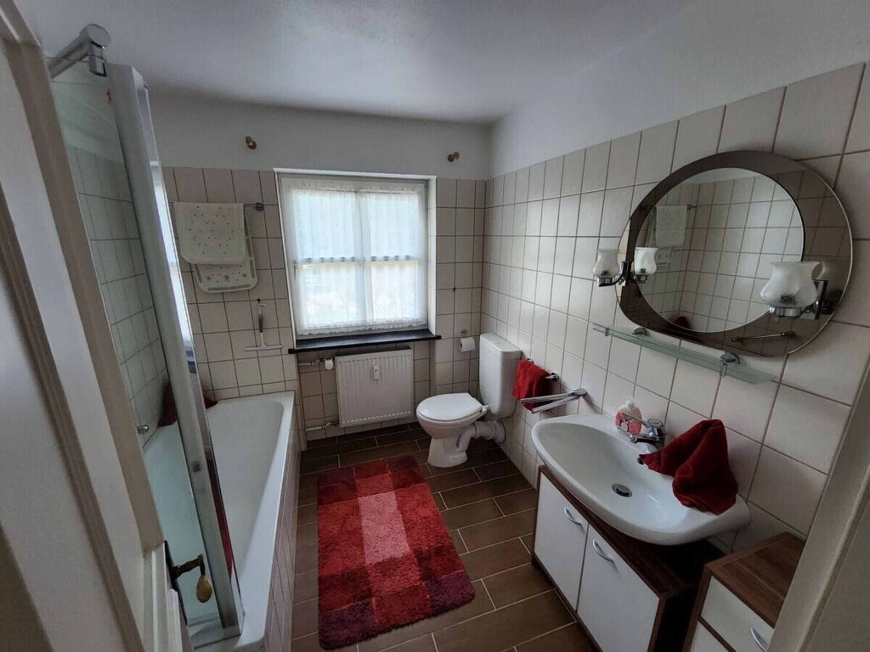 Un baño con bañera, inodoro, lavabo y ventana.