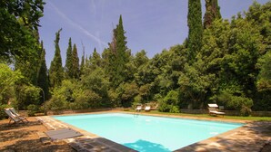 A rectangular swimming pool surrounded by a stone deck, with lounge chairs and a stone wall. - Belvilla by OYO Villa Topazio REQ (Cortona)