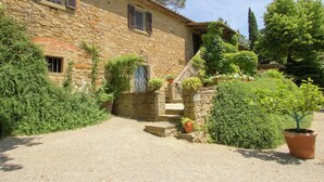 A stone building with a gravel driveway, a wooden gate, and a potted plant. - Belvilla by OYO Villa Topazio REQ (Cortona)