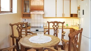 Ett kompakt kök med träskåp, en inbyggd ugn och ett matbord med stolar.