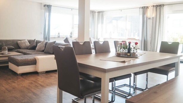 A modern living room with a sofa, dining table, and chairs. - Holiday Apartment Festungsberg (Koblenz)