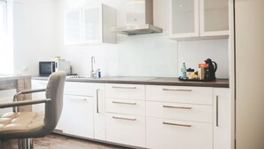 A modern kitchen with white cabinets, a stainless steel range hood, and a countertop with various appliances and items. - Holiday Apartment Festungsberg (Koblenz)