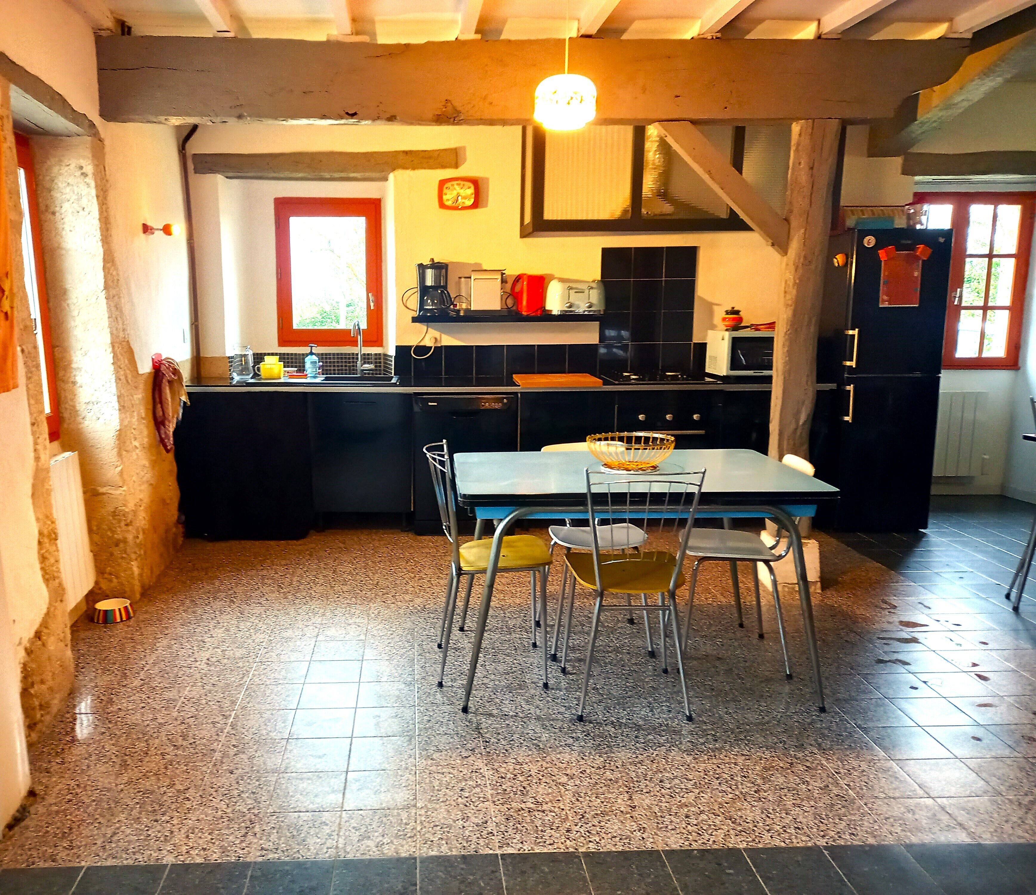 A kitchen with a dining table, chairs, and a hanging light fixture.