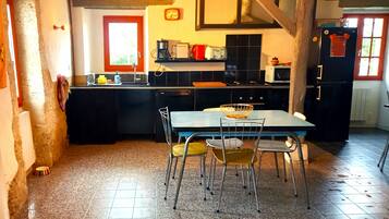A kitchen with a dining table, chairs, and a hanging light fixture.