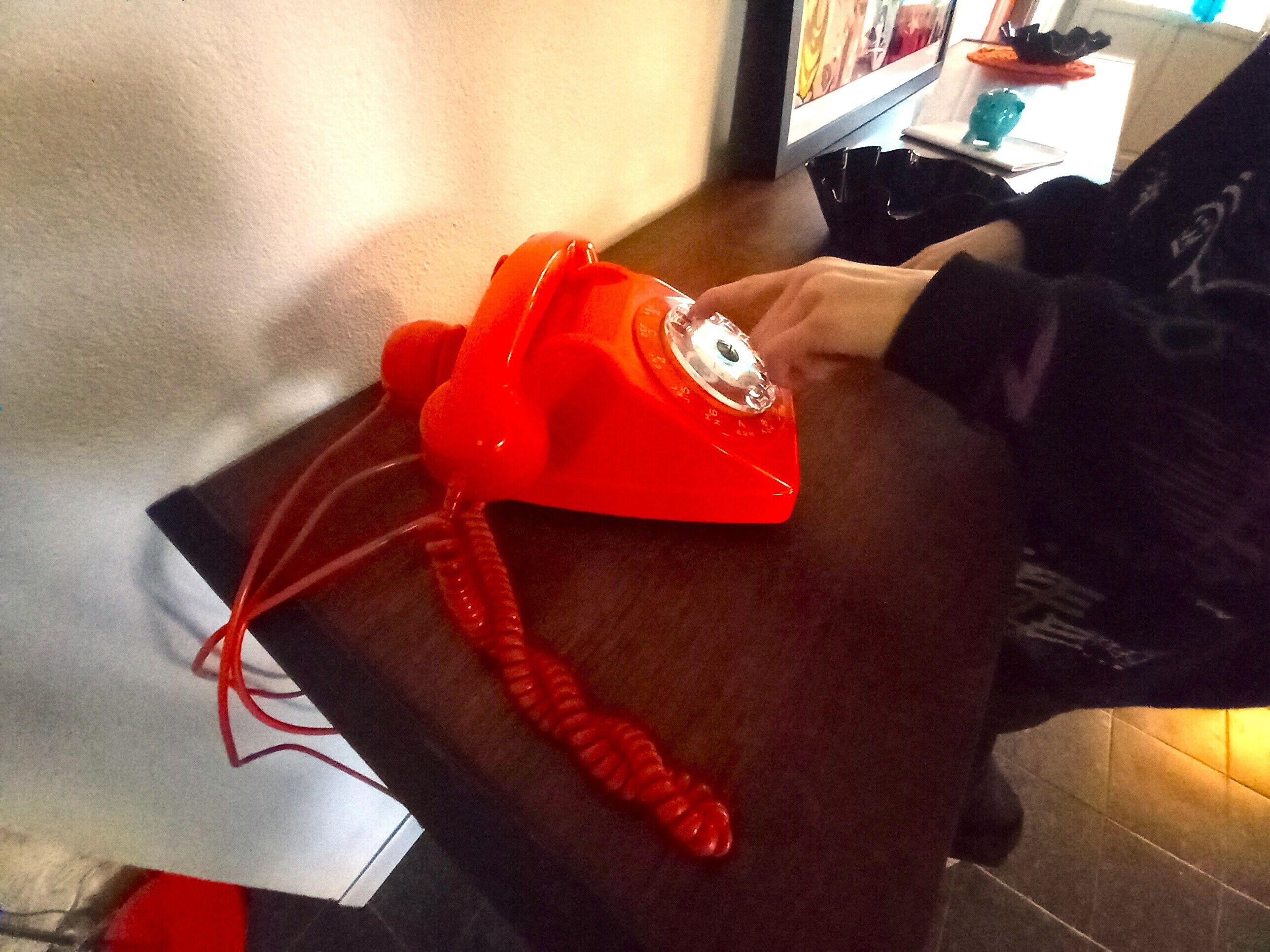Un téléphone à cadran rouge posé sur une table en bois.