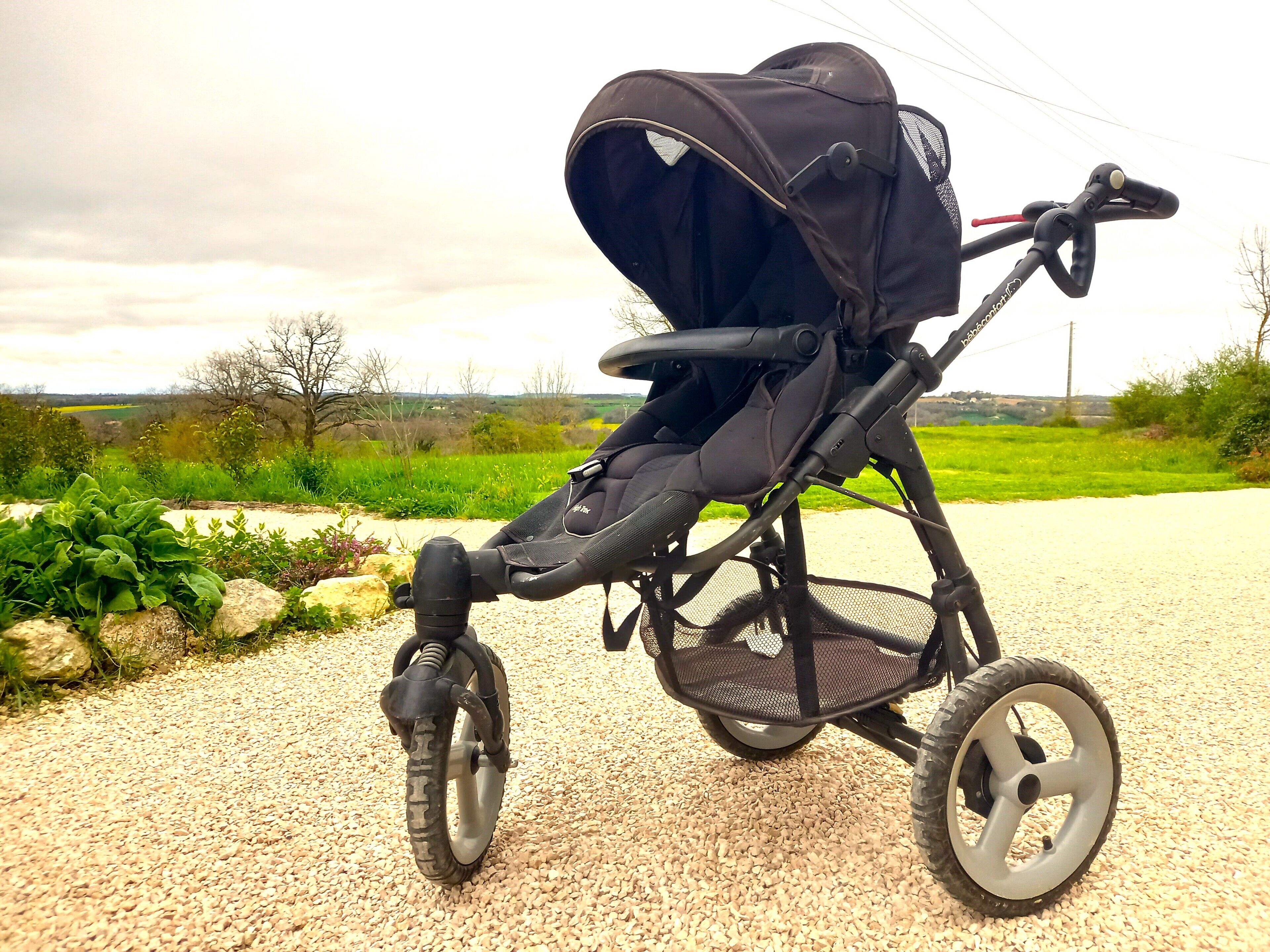 Ein Kinderwagen mit Verdeck, großen Rädern und einem Lenker.