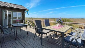 Eine Holzterrasse mit Tisch und Stühlen, ein kleines Gebäude mit Fenstern und eine Flagge.