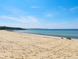 A beach with clear skies, calm water, and a few people in the distance.