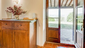 A wooden cabinet with drawers, a vase with red berries, and a wall-mounted lamp. - Belvilla by OYO Typical Country House With Pool (San Casciano dei Bagni)
