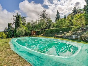 Relax by the serene pool surrounded by lush greenery and trees.
