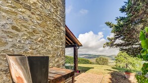 A stone wall, a grill, a wooden pergola, a potted plant, and a view of the countryside. - Belvilla by OYO Typical Country House With Pool (San Casciano dei Bagni)