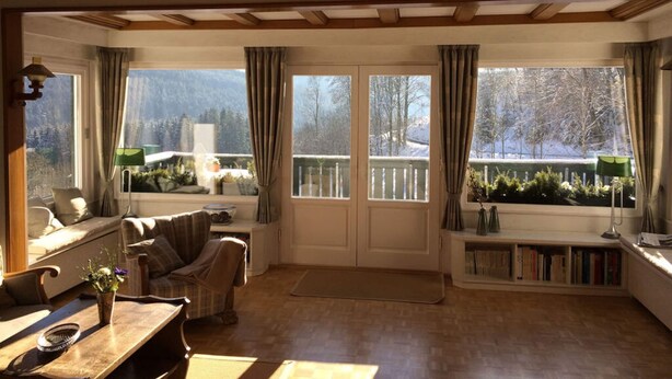 A cozy room with a wooden ceiling, a sofa, a coffee table, and a bookshelf. - Holiday Home Waldhaus am Burbach (Bad Berleburg)