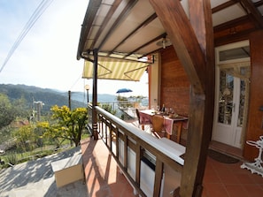 Ein Balkon mit Tisch und Stühlen, der einen schönen Blick auf Hügel und ein Gewässer bietet.