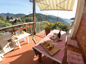 Eine Terrasse mit Esstisch, einer Weinflasche und Blick auf die Berge.