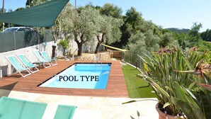 Una piscina rectangular con muelle de madera, rodeada de sillones de descanso y plantas en macetas.