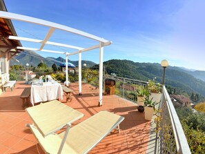 Eine Terrasse mit Esstisch, Lounge-Stühlen und Blick auf die Berge.
