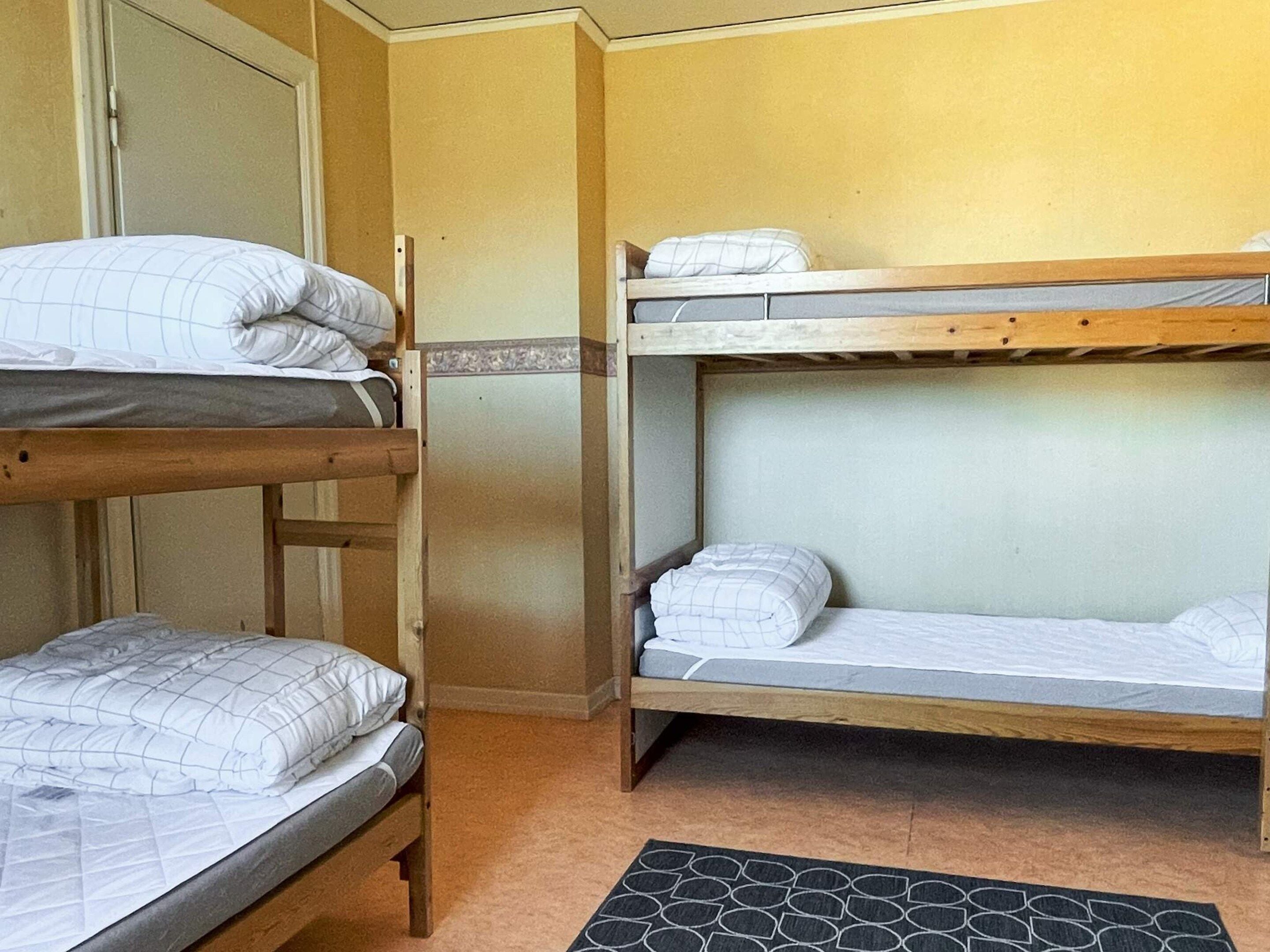 Habitación con literas, dos camas, una puerta y un tapete estampado.