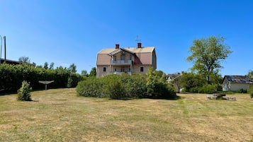 A two-story house with a sloped roof, surrounded by a grassy yard and a small tree.