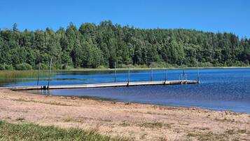 Un muelle a orillas de un lago tranquilo, rodeado de un denso bosque.