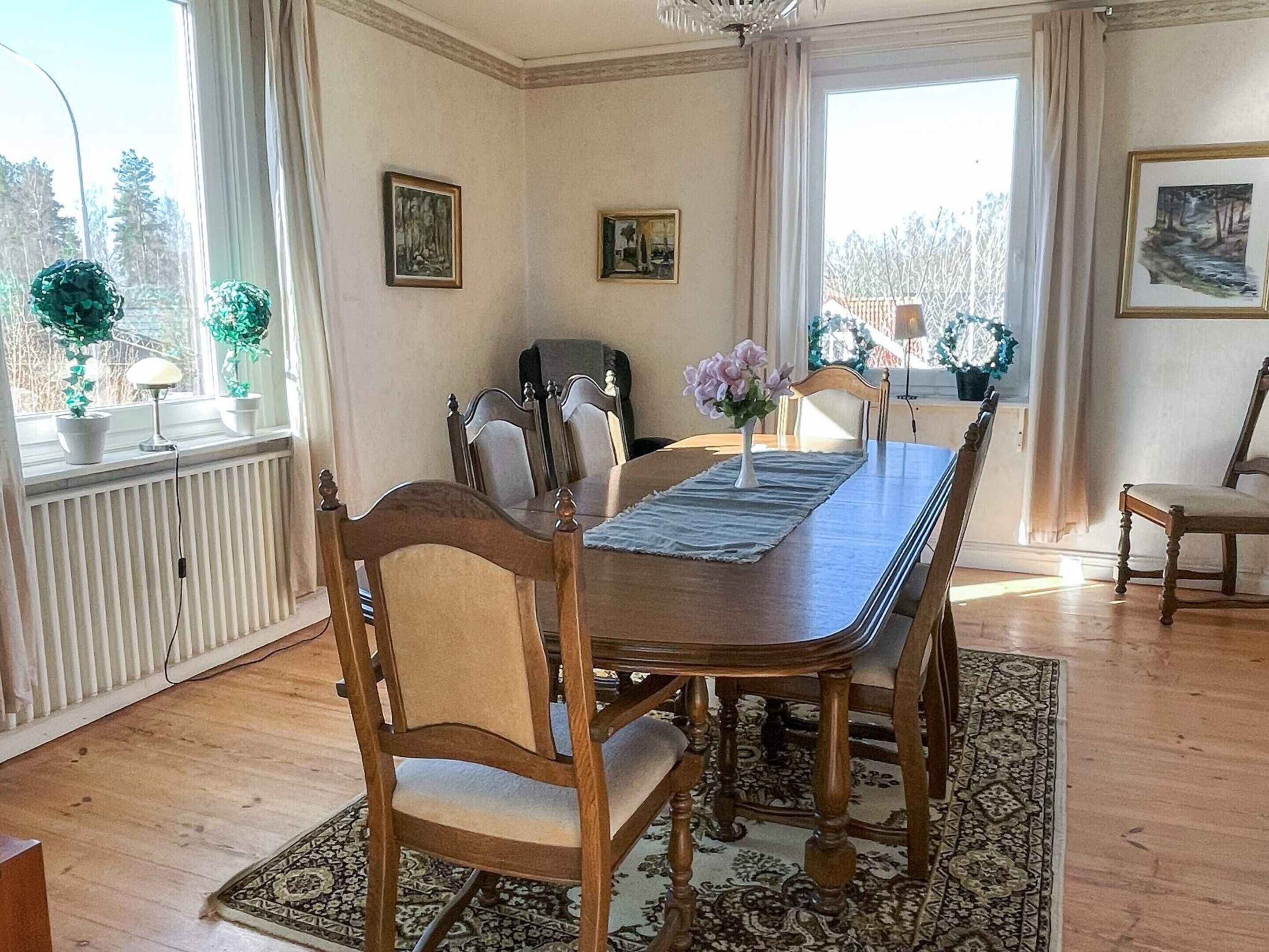 Une salle à manger avec une table en bois, des chaises, un lustre et des œuvres d’art accrochées aux murs.