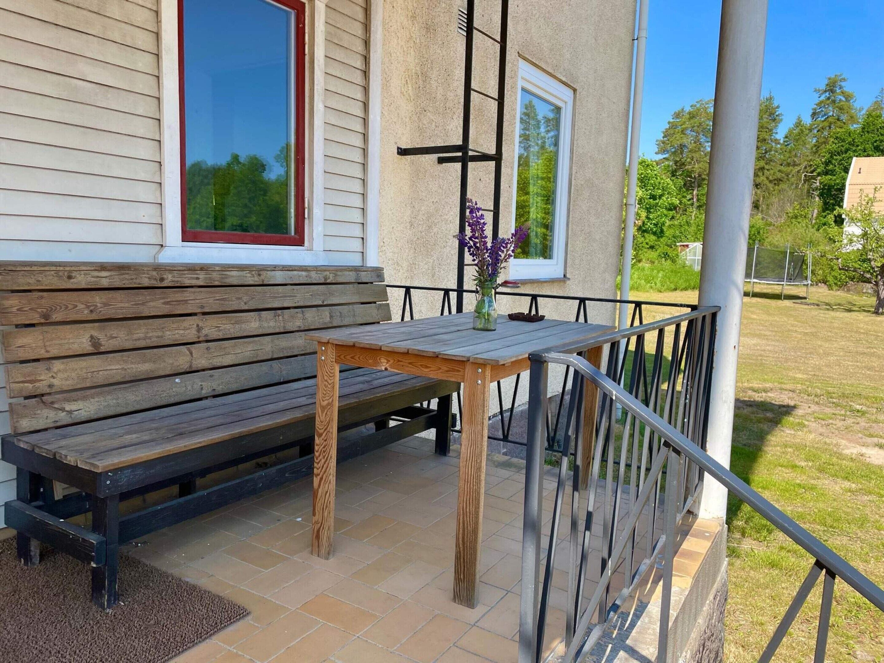 A wooden bench and table on a patio with a metal railing.