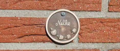 Un muro de ladrillo con una placa metálica que dice "Nelke".