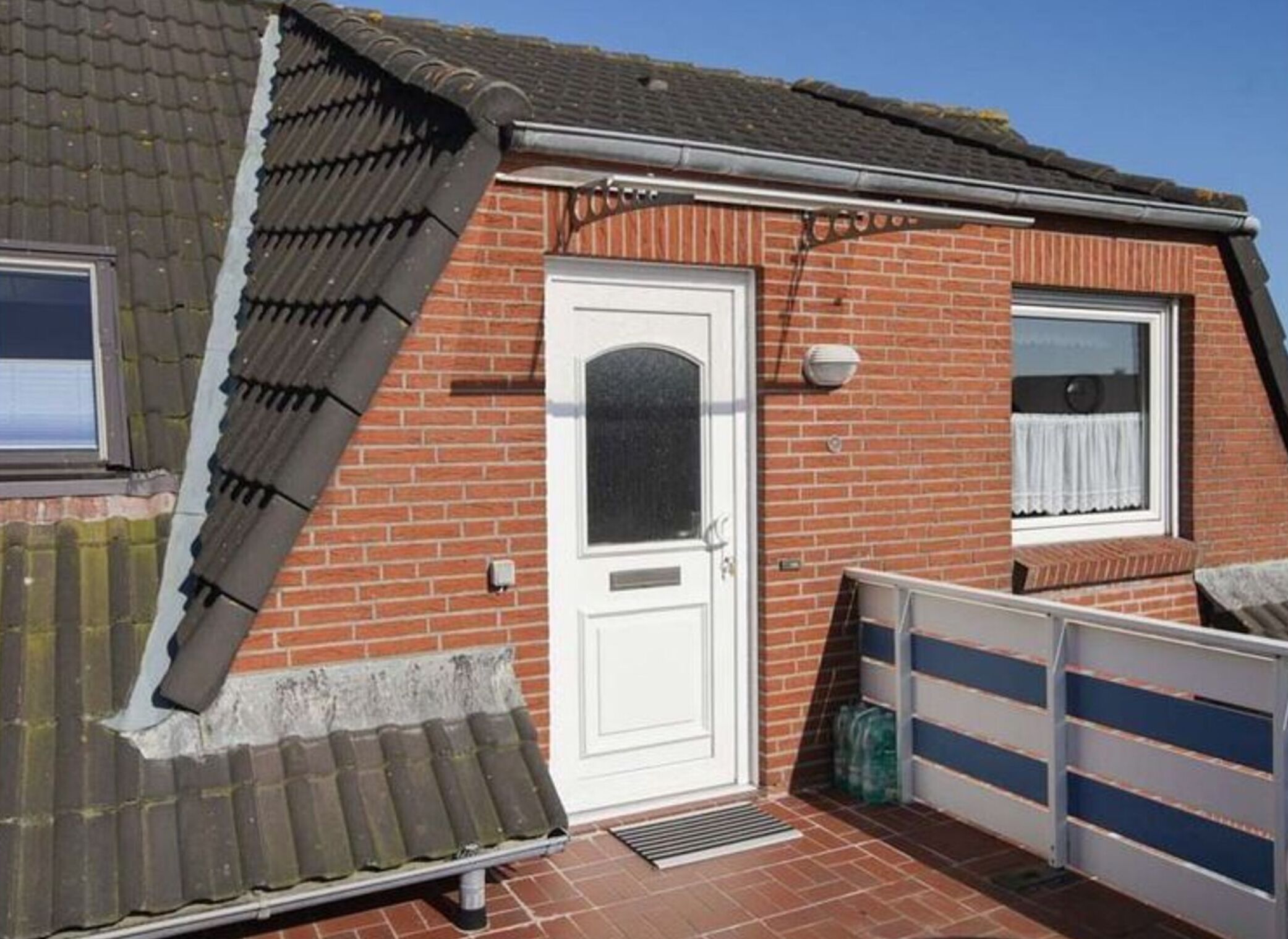 A red brick house with a white door, a small window, and a garage door.