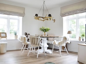 A dining area with a chandelier, white chairs, and a table. - Holiday Apartment Domstag "kos" (Kronsgaard)