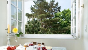 A breakfast table with a view of trees through a window. - "seashell" Modern Retreat (Binz)