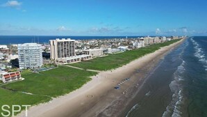 A coastal cityscape with a beachfront, buildings, and a clear sky. - Aquarius 408 2 Bedroom Condo by RedAwning (South Padre Island)